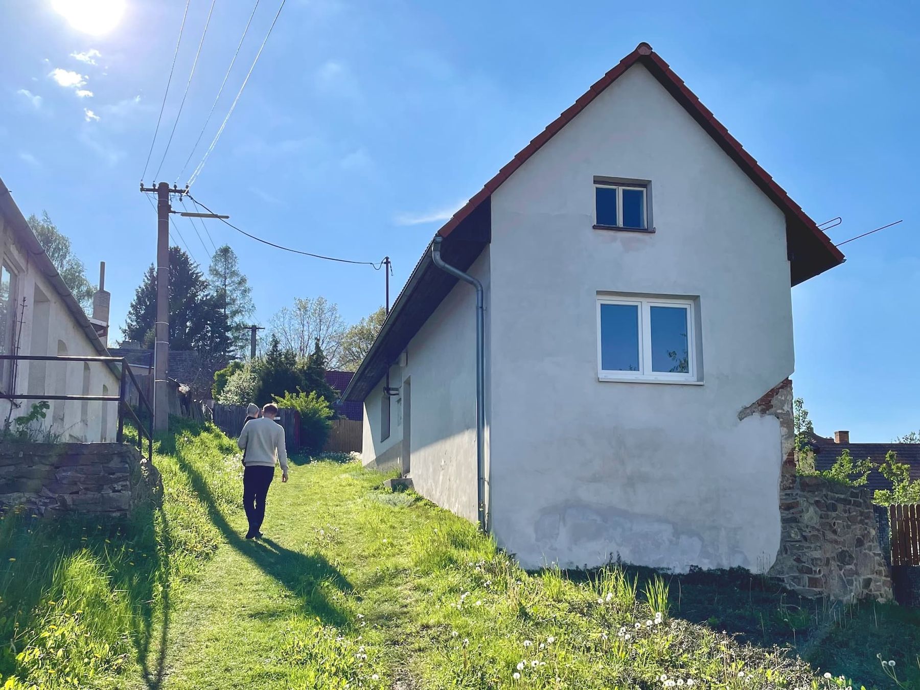 Bílý domek s trávníkem a cestičkou za domem