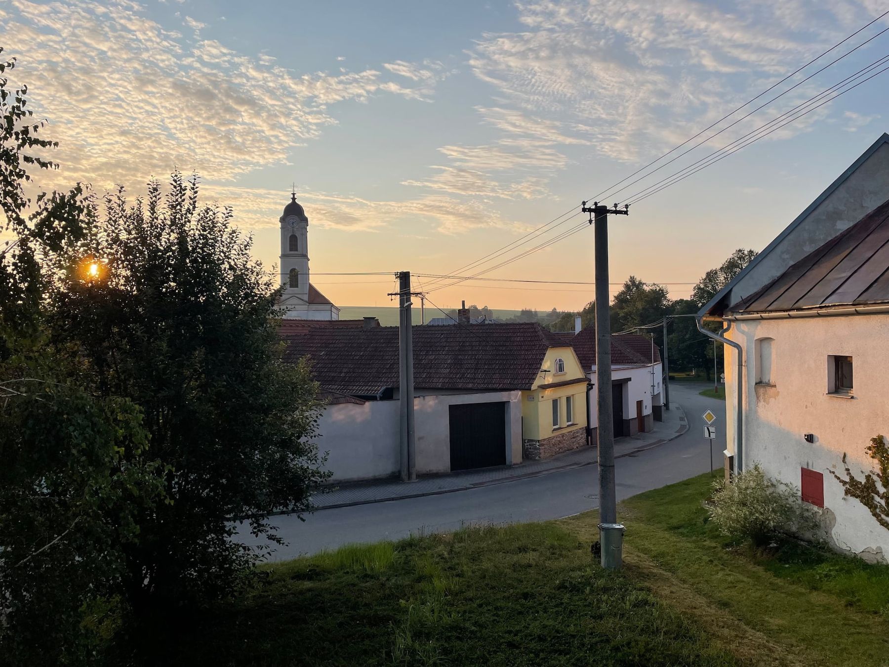 Západ slunce nad vesnicí s věží kostela